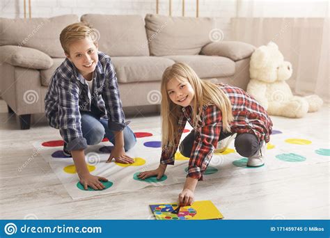 Cheerful Siblings Playing Twister Game On Floor Having Fun Indoor Stock