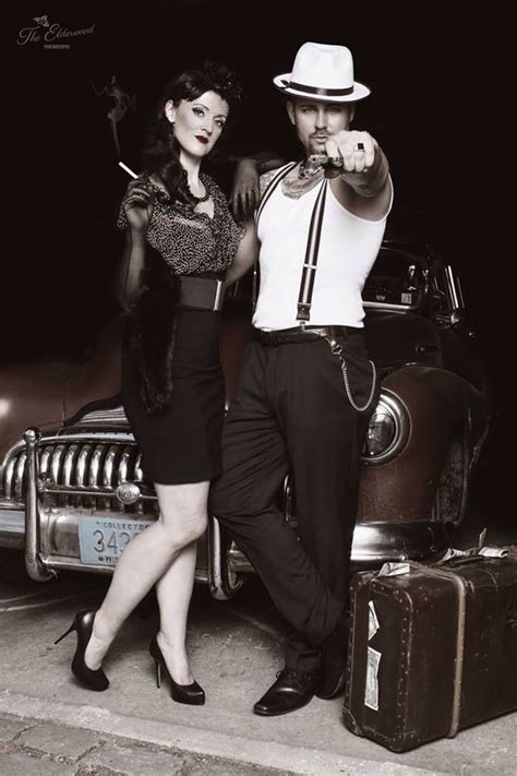 A Man And Woman Standing Next To An Old Car