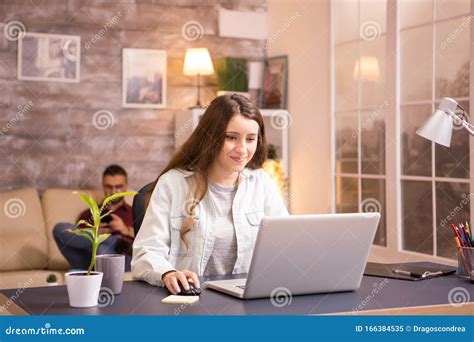 Cheerful Young Woman Smiling While Working On Laptop From Home Stock