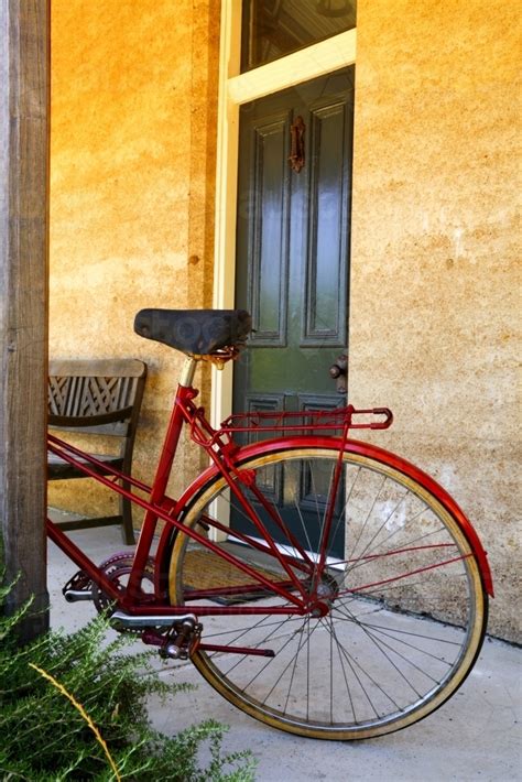 Image Of A Red Bicycle Parked Against A Post Outside A Cottage Entrance