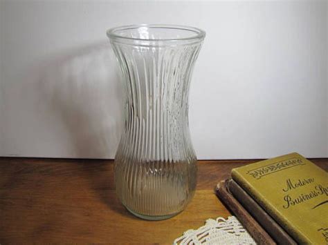 A Clear Glass Vase Sitting On Top Of A Wooden Table Next To Two Old Books