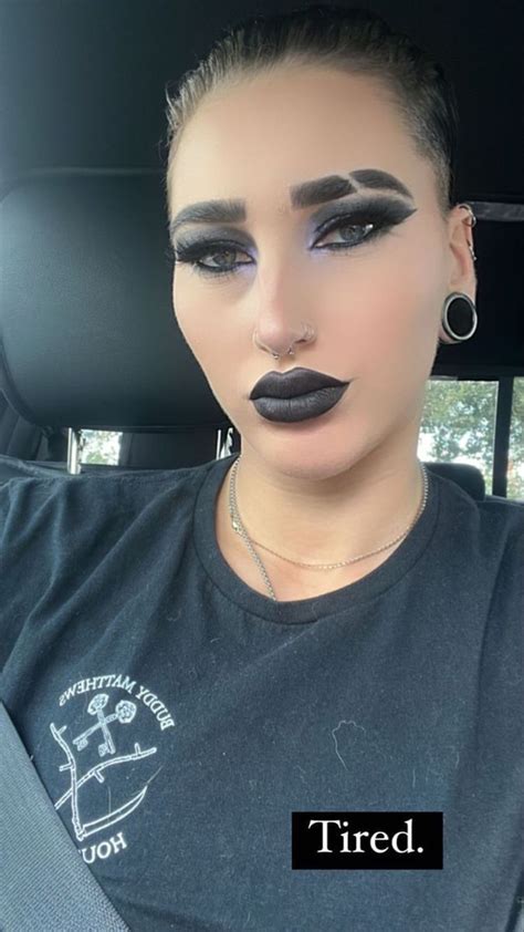 a woman with black lipstick on her face sitting in the back seat of a car