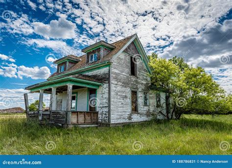 Old Abandoned Prairie Farmhouse With Trees Grass And Blue Sky In