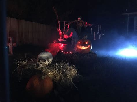 Two Pumpkins In The Grass With Lights On Them And A Skeleton Sitting