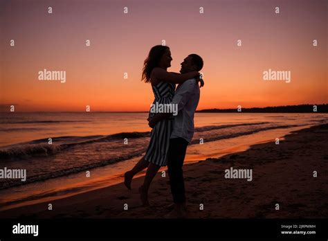 Silhouette Of A Couple Of Young Lovers Hugging On The Beach Duri Stock