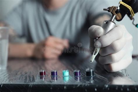 Tattoo Artist Dipping Machine Needle Into Ink At Table Stock Image