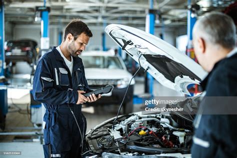 Auto Mechanic Working With Car Diagnostic Tool In A Repair Shop High