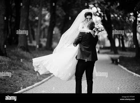 romantic newly married couple dancing in the park on their wedding day black and white photo