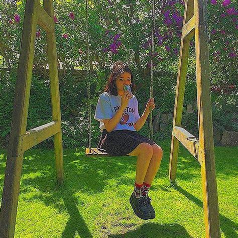 A Girl Sitting On A Swing In The Grass