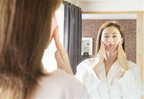 Portrait Of A Young Woman In White Bathrobe Who Makes Self Massage Of The Face Close Up Stock