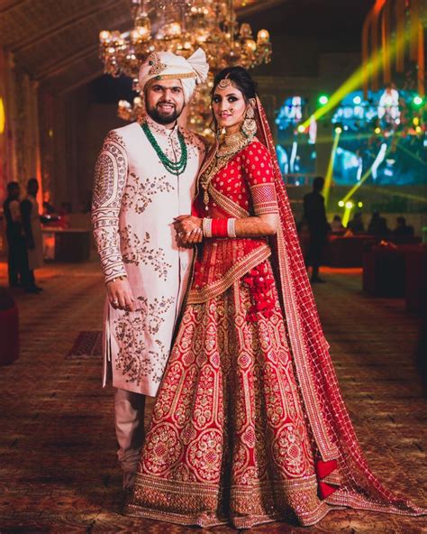 Photo Of Contrasting Bride And Groom Outfits In Red And White Indian Wedding Outfit Bride