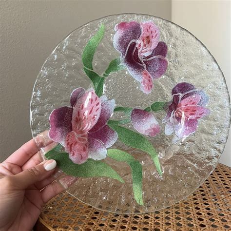 A Person Holding A Glass Plate With Flowers On It