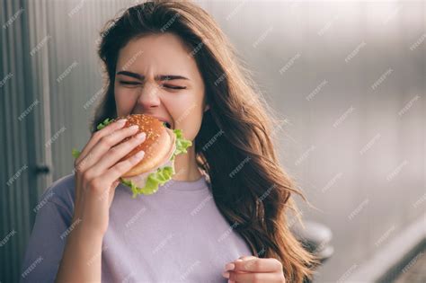 Premium Photo Hungry Woman Biting Piece Of Burger