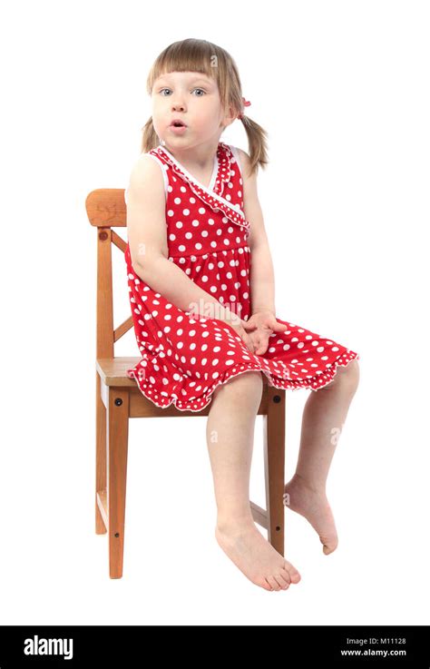 Surprised Little Baby Girl In Red Dress Sitting On A Chair Isolated On