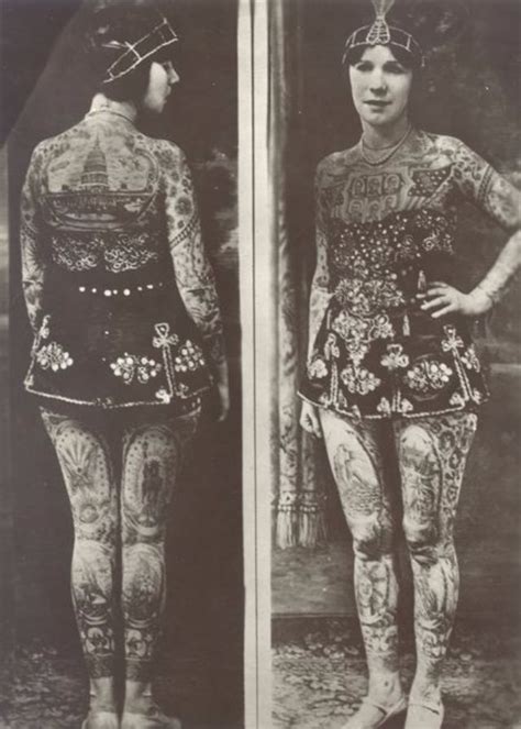 an old black and white photo of a woman with tattoos on her back standing in front of a mirror