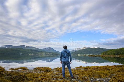 A Man Looks At The Mountains And Lakes Reflecting The Still Water Like