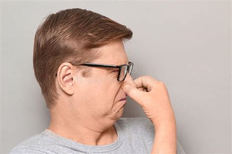 Portrait Of Mature Man Pinching His Nose And Grimacing From Disgust
