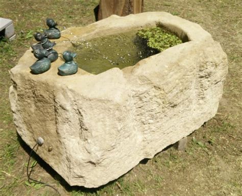 Plätscherndes wasser in einem natursteinbrunnen oder ein quellstein, aus dem wasser sprudelt, schenkt ihrem garten erholungswert. Natursteinbrunnen im Garten