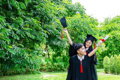 A Man And Woman Couple Dressed In Black Graduation Gown Or Graduates With Congratulations With