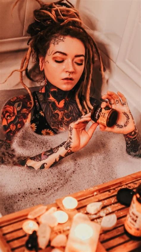 a woman with dreadlocks sitting in front of a bath tub holding a camera