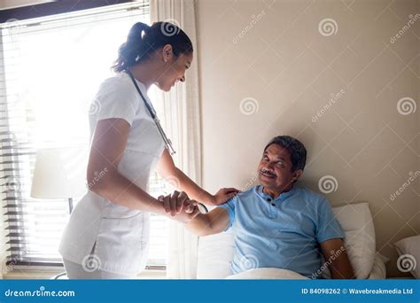 Female Doctor Interacting With Senior Patient In Bedroom Stock Photo