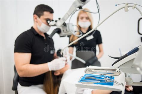Male Dentist And Female Assistant Treating Patient Teeth With