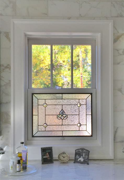 A Bathroom Window With A Stained Glass Design On Its Side And The Sink Below