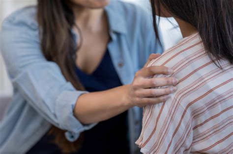 Close up photo of mom’s comforting hand on daughter’s shoulder