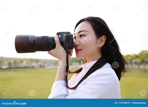 close up aisan chinese woman photographer hold camera close to her face work in nature against