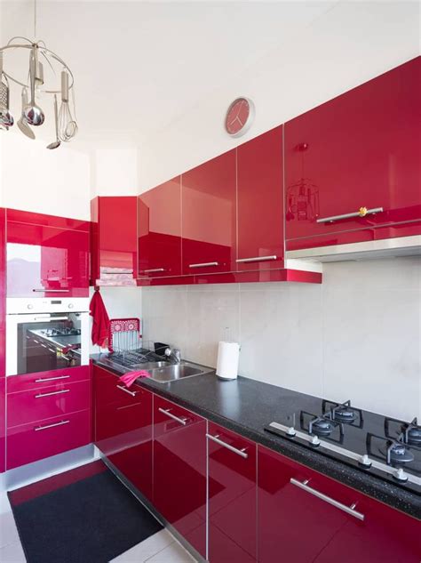 A Kitchen With Red Cabinets And Black Counter Tops
