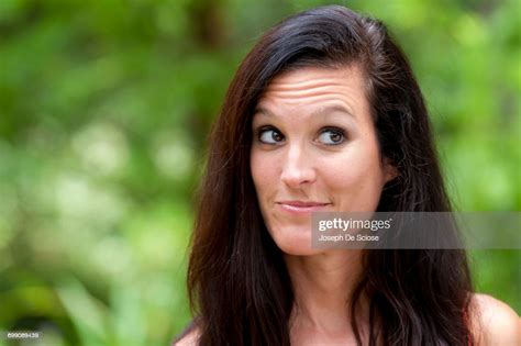 a 38 year old brunette woman outdoors making a face looking away from the camera high res stock