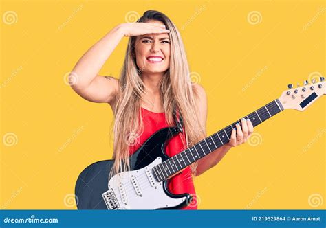 Young Beautiful Blonde Woman Playing Electric Guitar Stressed And