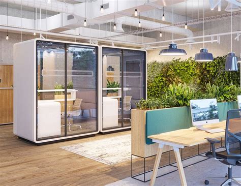 An Office With Plants On The Wall And Desks In Front Of It Along With