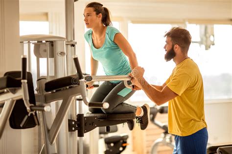 Gym Woman Exercise Muscles With Assisting Her Personal Trainer Stock Image Image Of Strength
