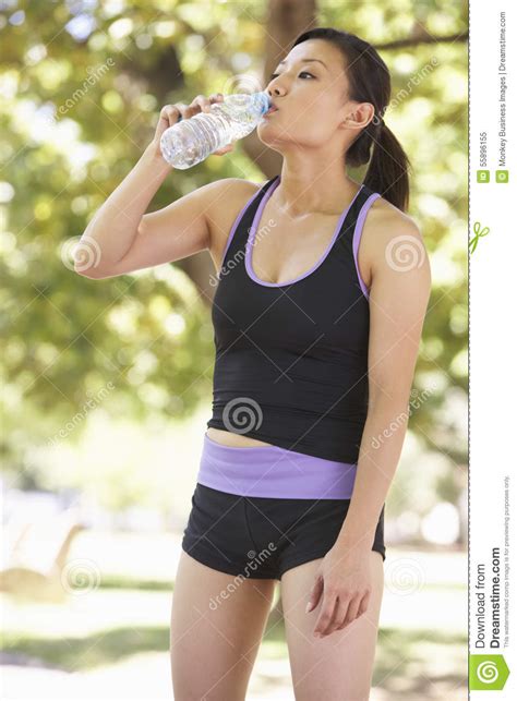 Young Woman Drinking Water Whilst Exercising In Park Stock Image