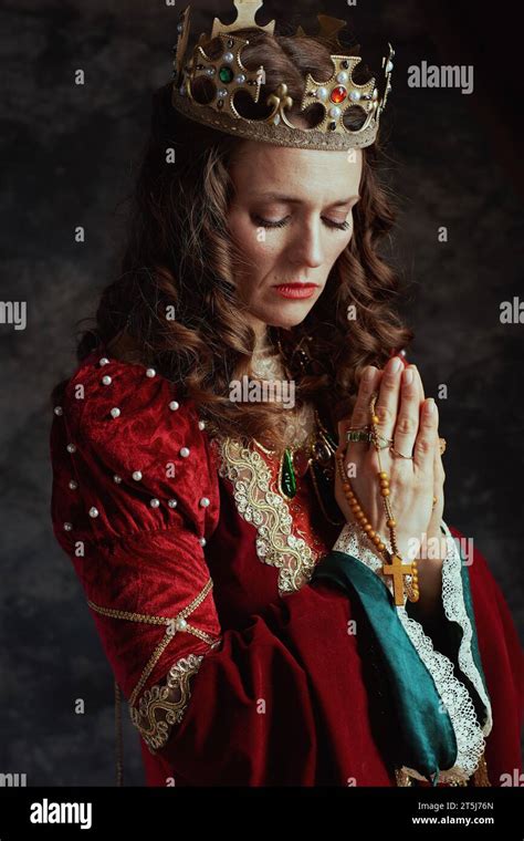 Medieval Queen In Red Dress With Rosary And Crown Praying On Dark Gray