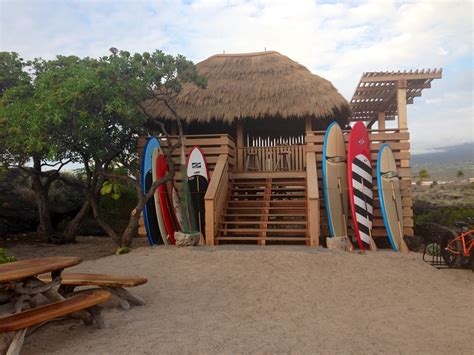 Surfboards Are Lined Up In Front Of A Tiki Hut With Stairs And Benches