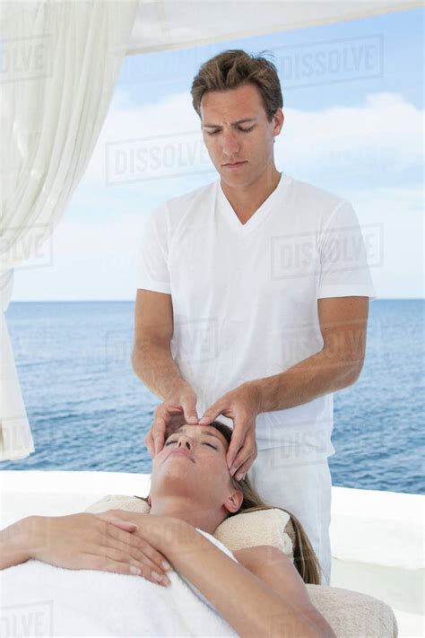 Male Masseur Giving Young Woman A Head Massage At Beach Resort Majorca