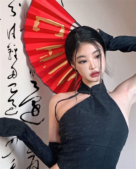 a woman in a black dress and red fan with writing on the wall behind her