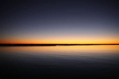 Silhouette Of Calm Sea Under Blue And Orange Clear Sky During Sunset