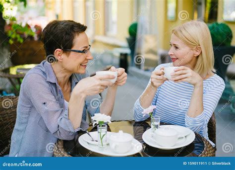 Mature Ladies Drinking Coffee And Talking In Open Air Cafe On Summer
