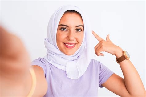 beautiful arabian girl wearing hijab make selfie by camera over isolated white background very
