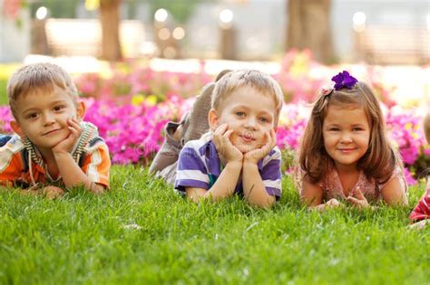 Drie Gelukkige Kinderen Die Op Het Gras Liggen Stock Afbeelding Image