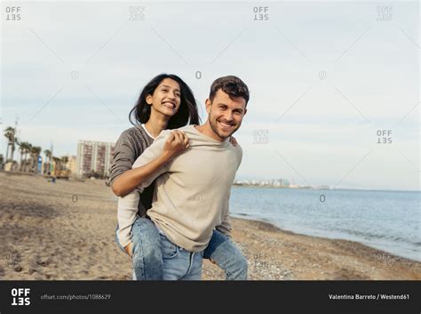 Smiling Boyfriend While Giving Piggyback Ride To Girlfriend At Beach