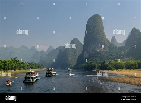 Tour Boats Traveling Down The Li River Guangxi China With Tall Karst