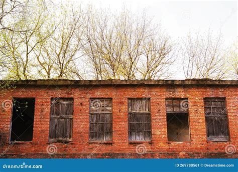 Wall Of An Old Red Brick House With Empty And Boarded Up Windows