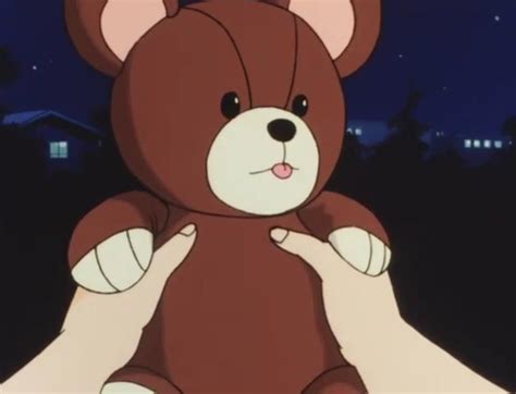 A Person Holding A Brown Teddy Bear In Their Left Hand At Night With