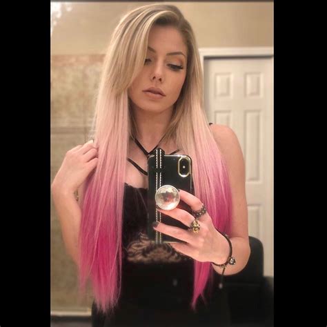 a woman with pink hair is taking a selfie