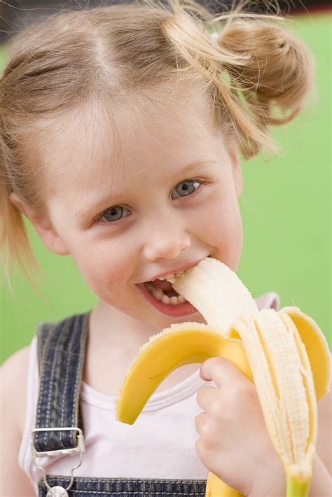 Little Girl Eating Banana Ottieni La Licenza Per Le Foto 969917