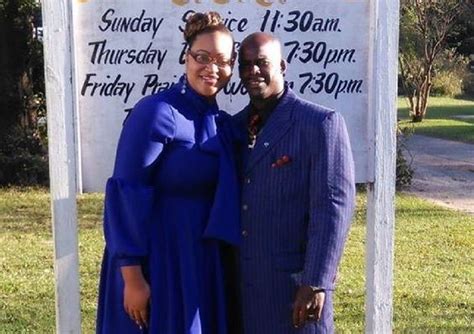A Man And Woman Pose For A Photo In Front Of A Sign That Says Sunday Service 11 30am